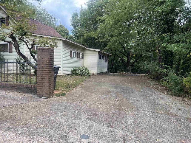 view of side of property with fence and driveway
