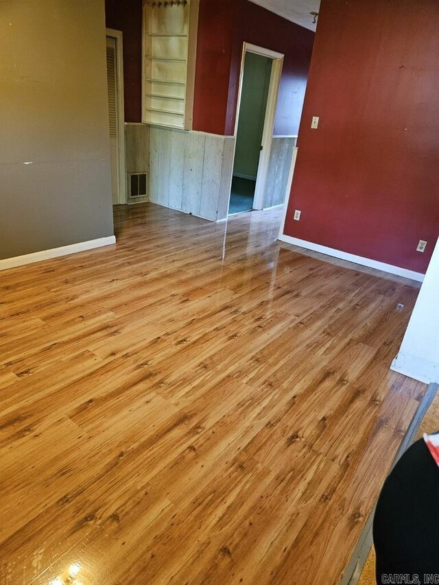 unfurnished room featuring baseboards, wood finished floors, and visible vents