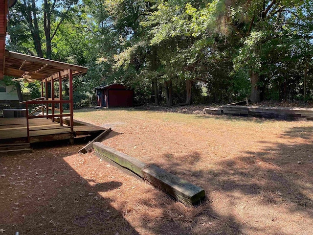 view of yard featuring a storage unit, ceiling fan, and a deck