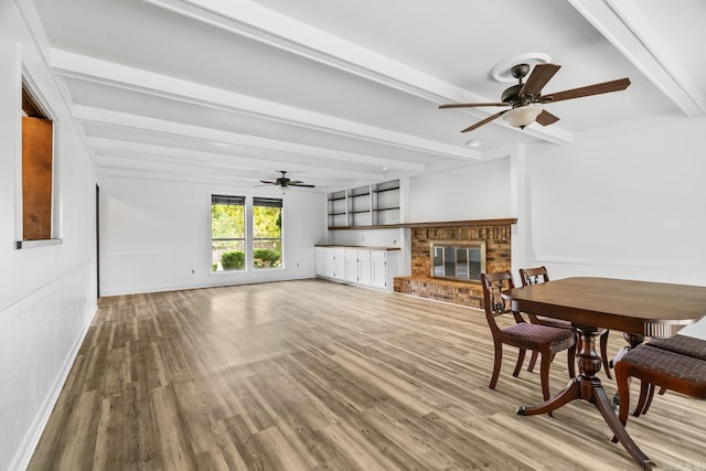 living room with ceiling fan, wood-type flooring, beam ceiling, and a fireplace