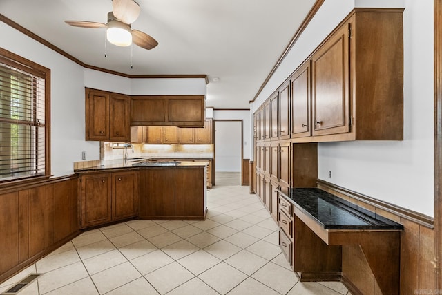 kitchen with light tile patterned floors, sink, kitchen peninsula, ceiling fan, and ornamental molding