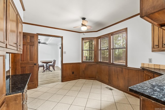 kitchen featuring dark stone countertops, crown molding, ceiling fan, and light hardwood / wood-style floors