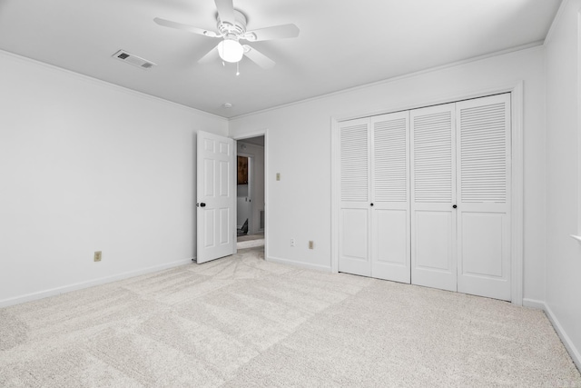 unfurnished bedroom featuring light carpet, crown molding, ceiling fan, and a closet