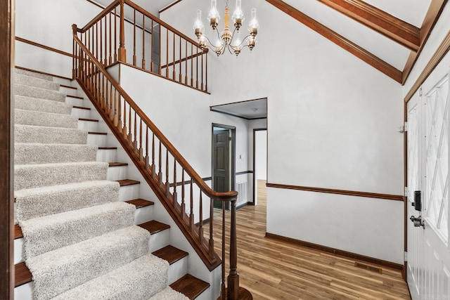 stairway featuring hardwood / wood-style floors, high vaulted ceiling, a wealth of natural light, and an inviting chandelier