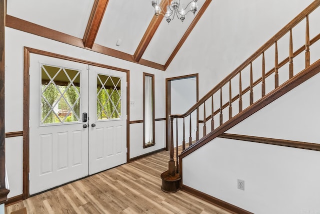 entrance foyer with french doors, light wood-type flooring, a chandelier, and lofted ceiling with beams