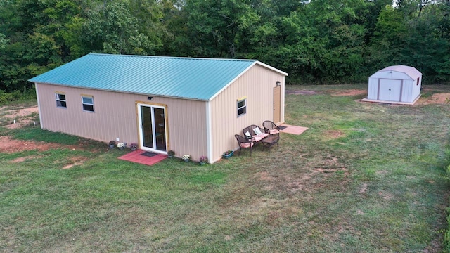 exterior space with an outbuilding, a shed, a view of trees, a lawn, and metal roof