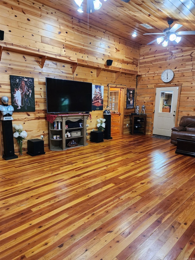 living room with ceiling fan, wooden walls, and hardwood / wood-style flooring