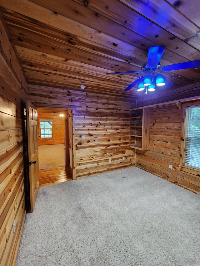 unfurnished room with wooden ceiling, wood walls, ceiling fan, and carpet