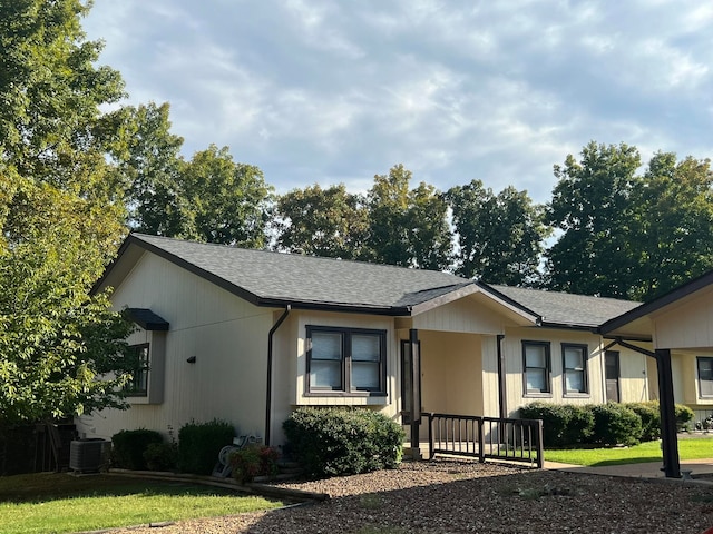 ranch-style home with central air condition unit and a front yard