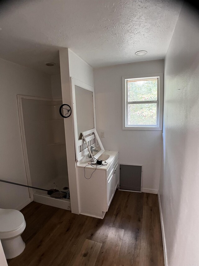 bathroom with vanity, toilet, hardwood / wood-style floors, and a shower