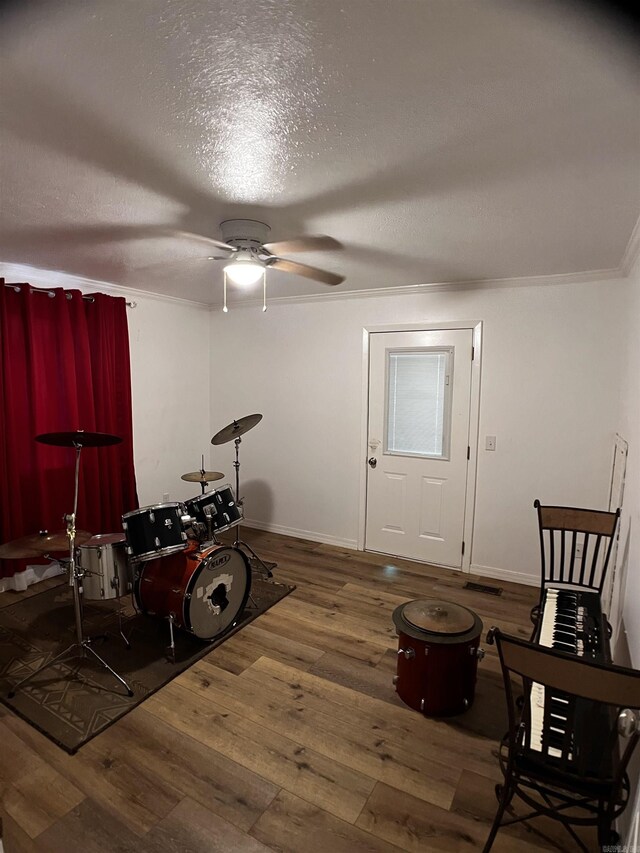 interior space with ceiling fan, hardwood / wood-style flooring, a textured ceiling, and ornamental molding