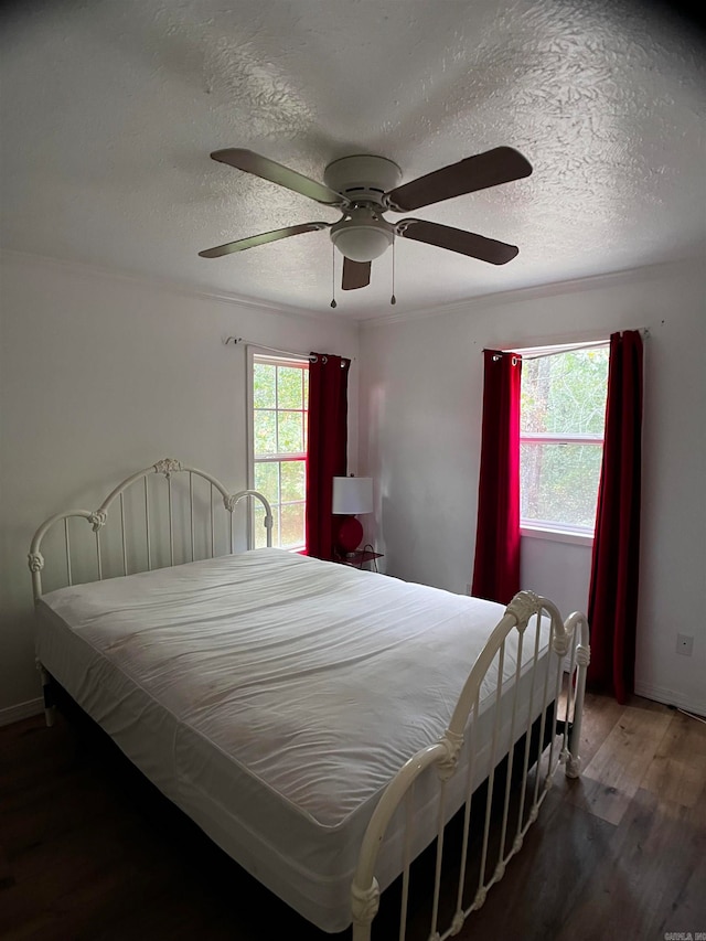 bedroom with a textured ceiling, ceiling fan, and hardwood / wood-style floors