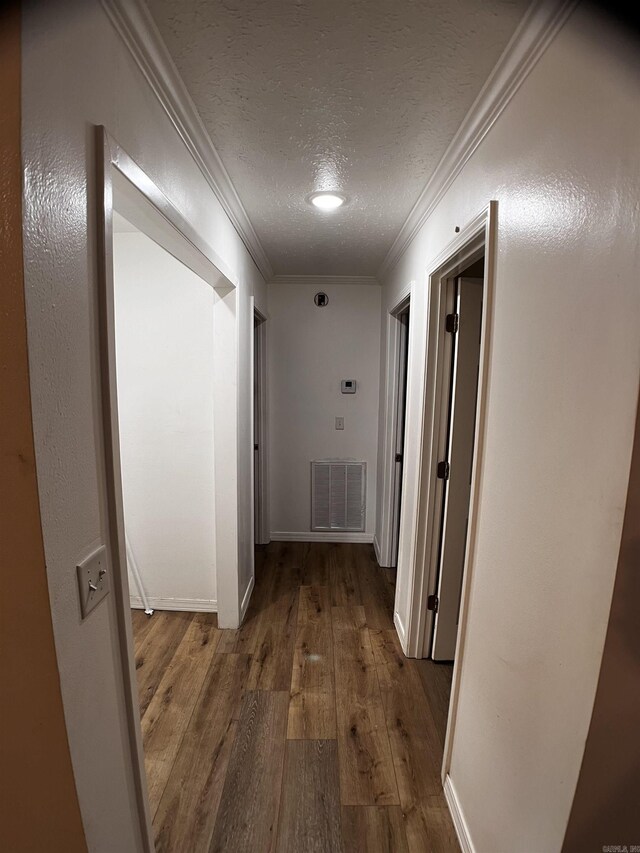 corridor with hardwood / wood-style floors, ornamental molding, and a textured ceiling