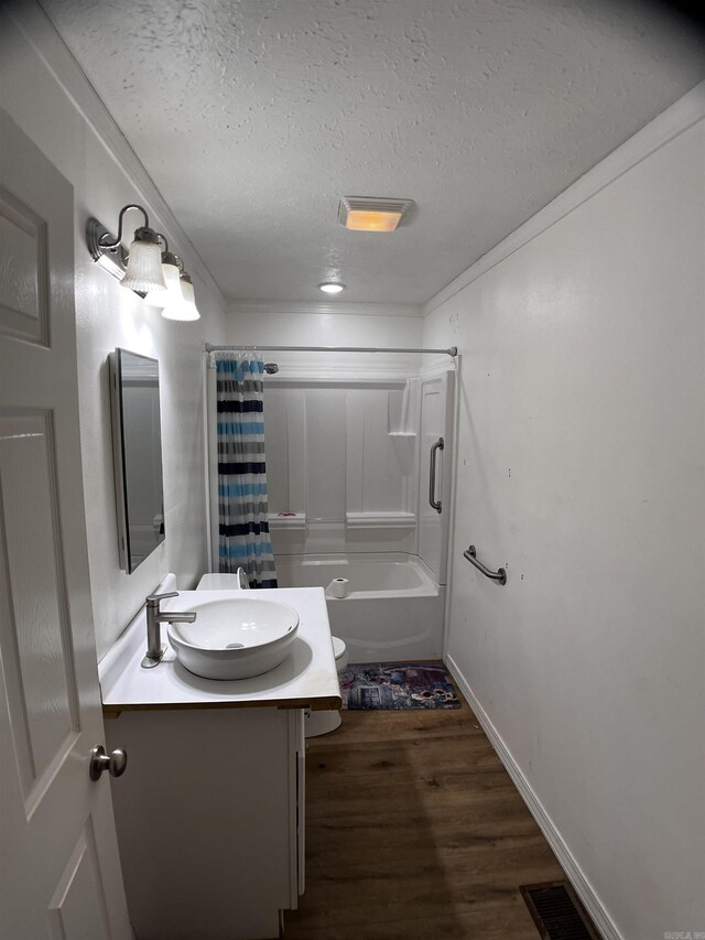 bathroom with crown molding, vanity, a textured ceiling, shower / bath combo, and hardwood / wood-style flooring