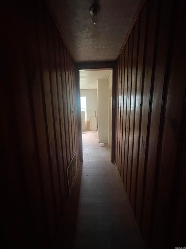 hall with light wood-type flooring and wood walls