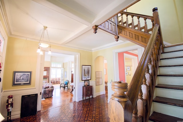 stairway featuring hardwood / wood-style floors, beamed ceiling, and ornamental molding