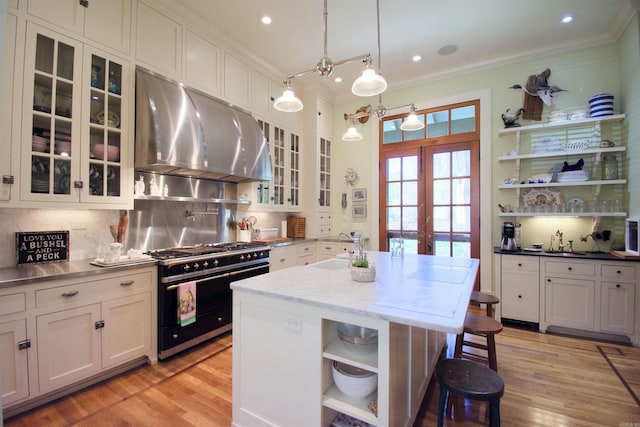 kitchen featuring a breakfast bar, a center island with sink, stainless steel stove, and light hardwood / wood-style floors