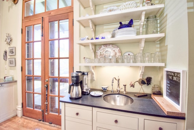 bar featuring white cabinetry, sink, and light hardwood / wood-style floors