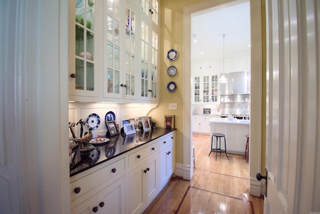 bar with light hardwood / wood-style flooring, decorative backsplash, and white cabinetry