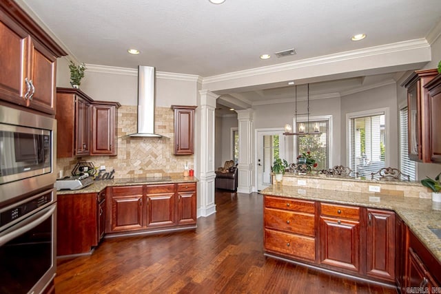 kitchen with dark hardwood / wood-style flooring, light stone counters, wall chimney exhaust hood, appliances with stainless steel finishes, and ornate columns