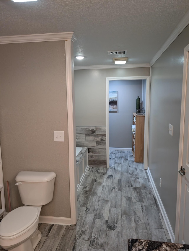 bathroom with crown molding, toilet, wood-type flooring, and a textured ceiling