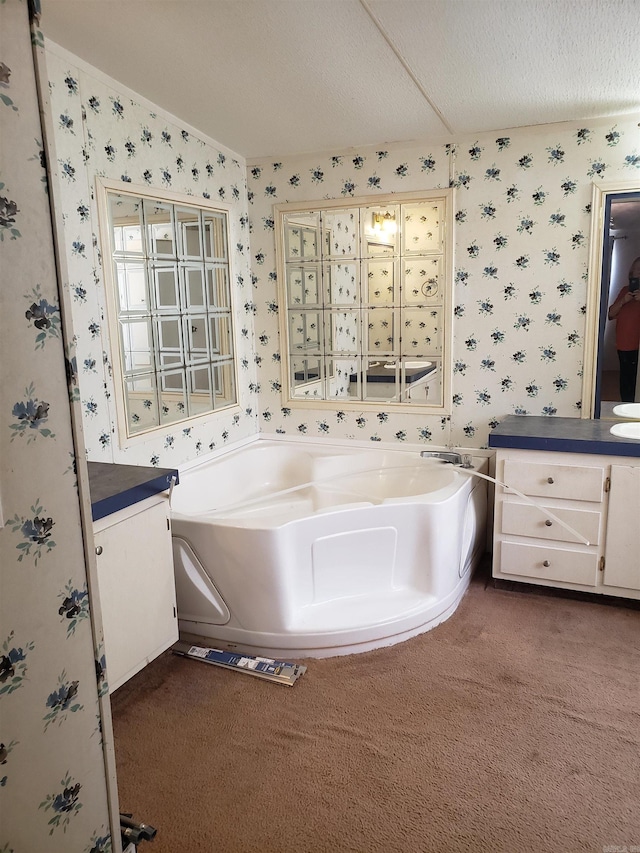 bathroom with a textured ceiling, vanity, and a tub