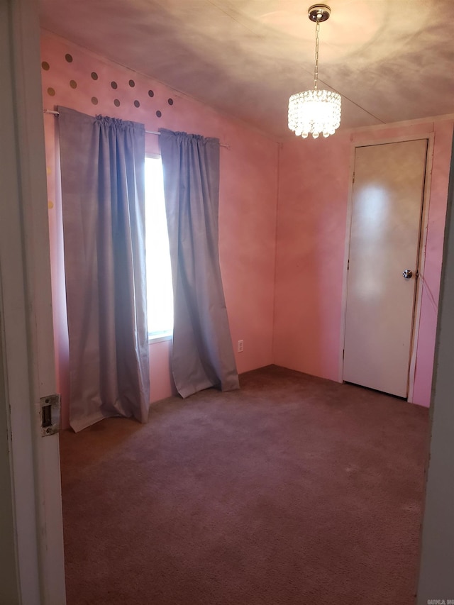 carpeted spare room featuring a notable chandelier