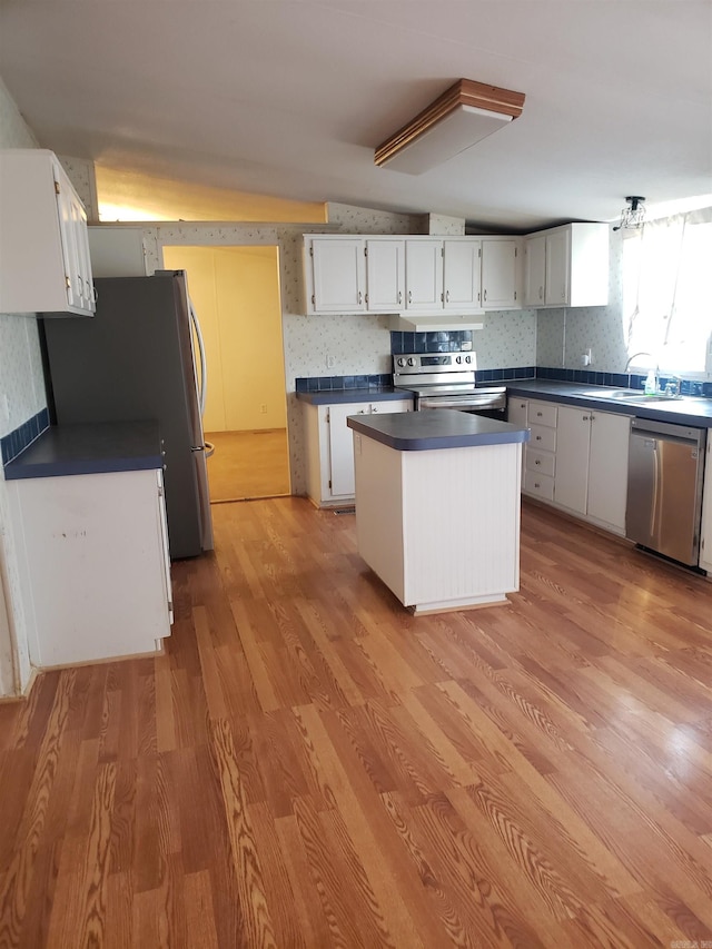 kitchen featuring light hardwood / wood-style flooring, stainless steel appliances, vaulted ceiling, and white cabinets
