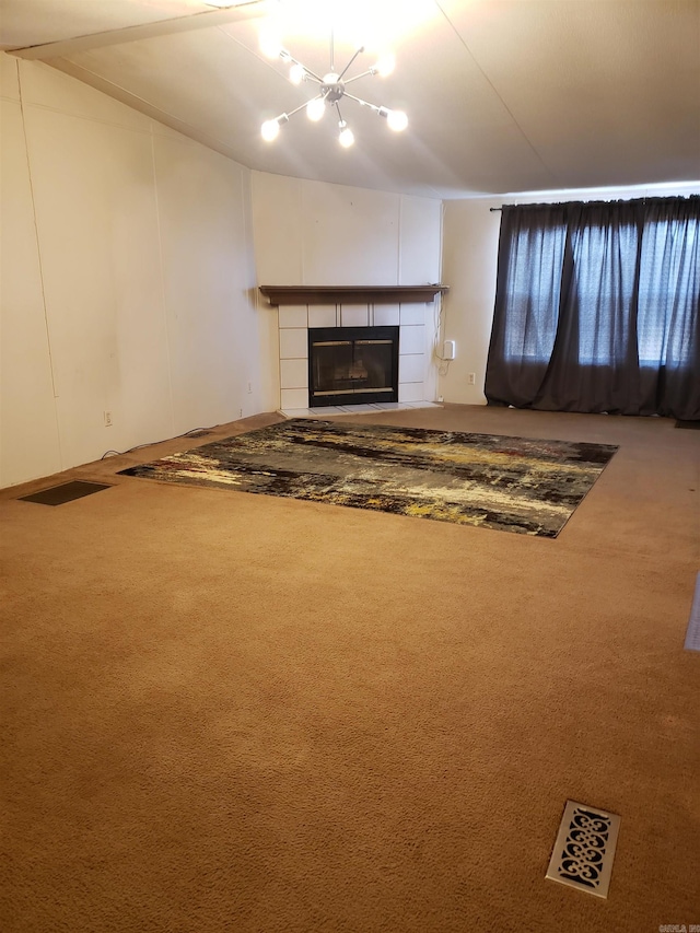unfurnished living room with carpet flooring, a tile fireplace, and an inviting chandelier