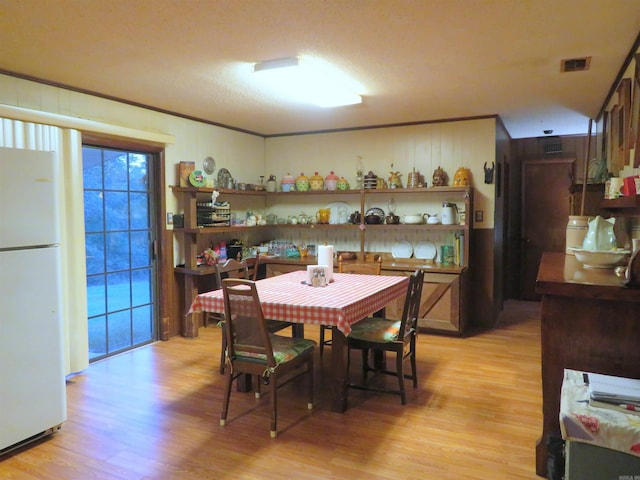 dining space featuring a textured ceiling and light wood-type flooring