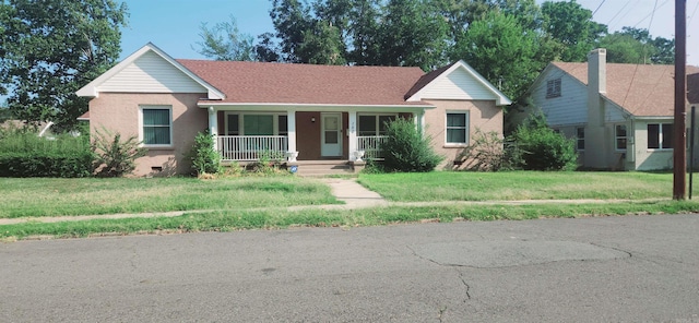 ranch-style home featuring a front lawn and covered porch