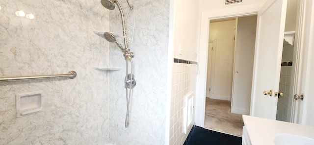 bathroom featuring tiled shower and vanity