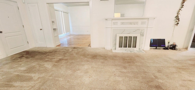 unfurnished living room with light colored carpet and a premium fireplace