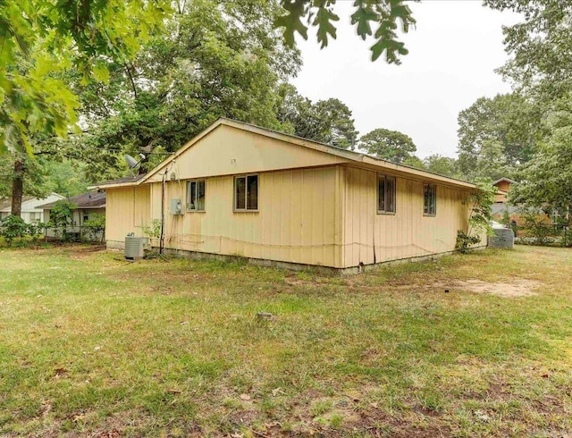 view of side of home featuring a lawn and central AC