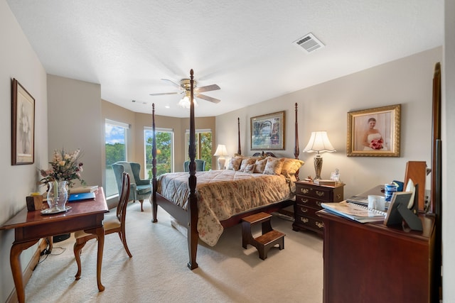 bedroom with light colored carpet, ceiling fan, and a textured ceiling