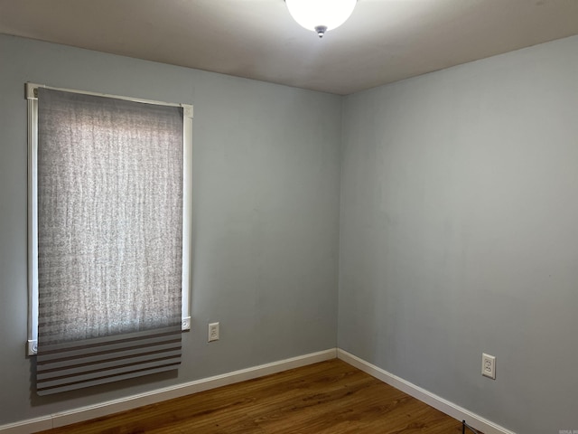 spare room with baseboards and wood finished floors