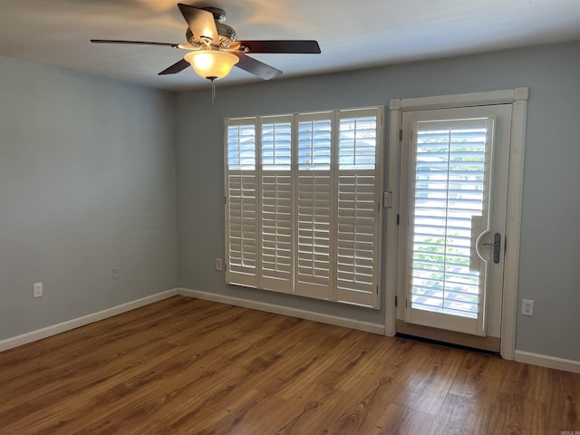 unfurnished room featuring wood finished floors, baseboards, a ceiling fan, and a wealth of natural light