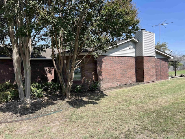 view of side of property featuring brick siding and a yard