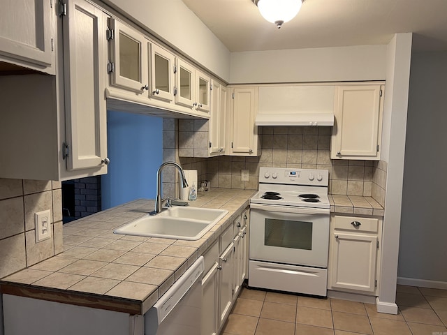 kitchen with tile counters, white appliances, light tile patterned floors, white cabinetry, and a sink