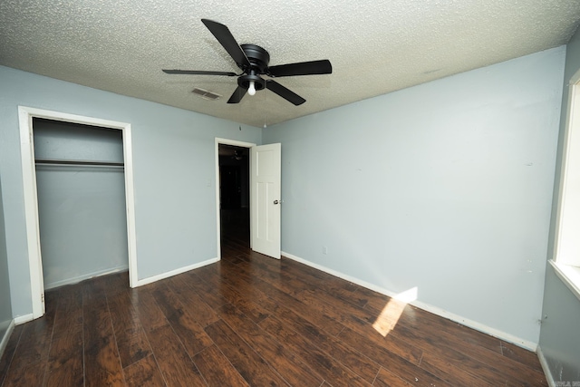 unfurnished bedroom with a textured ceiling, ceiling fan, a closet, and dark hardwood / wood-style flooring