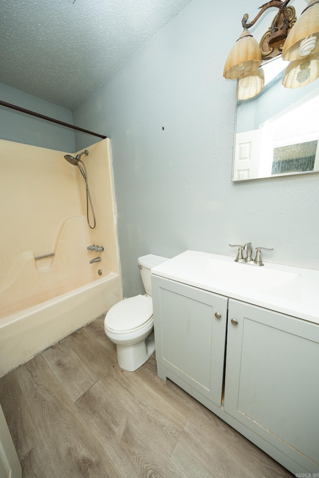 full bathroom featuring toilet, vanity, a textured ceiling, wood-type flooring, and bathing tub / shower combination