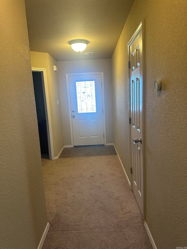 doorway to outside with light carpet and a textured ceiling