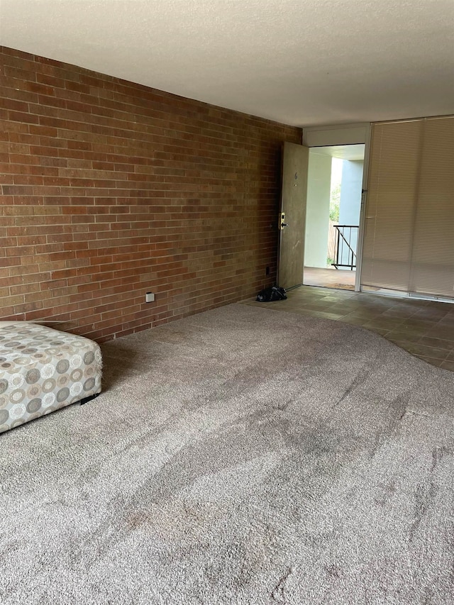 interior space featuring carpet, a textured ceiling, and brick wall