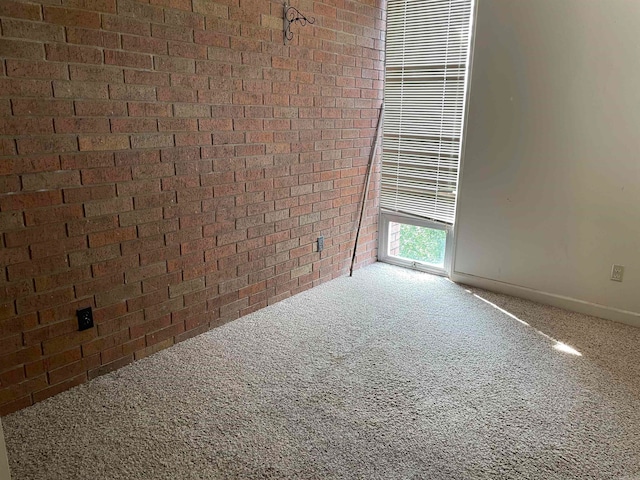 empty room featuring carpet and brick wall