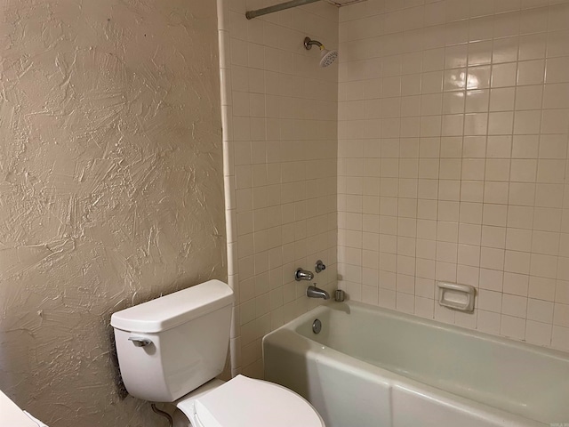 bathroom featuring tiled shower / bath combo and toilet