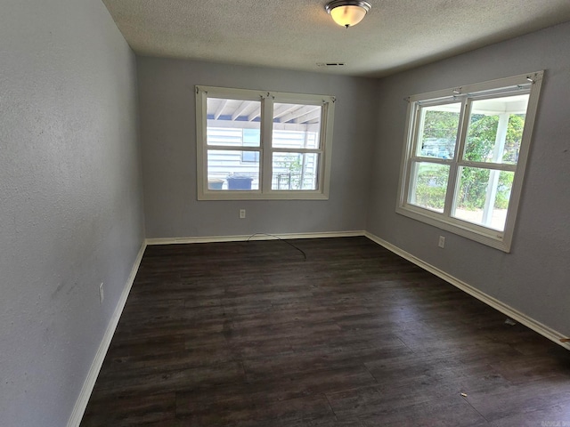 empty room featuring a textured ceiling and dark hardwood / wood-style floors