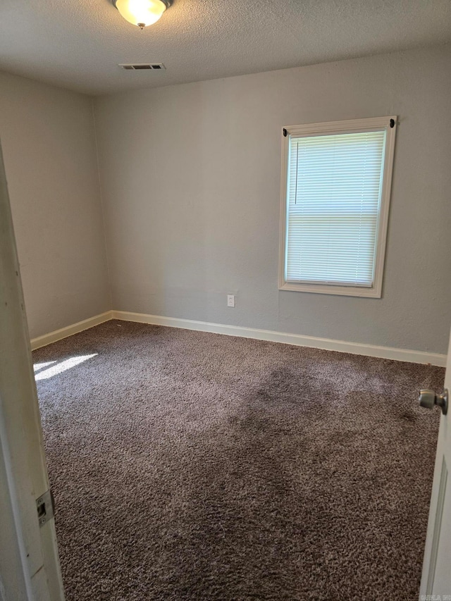 carpeted empty room with a textured ceiling