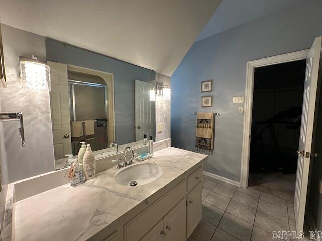 bathroom with vanity, lofted ceiling, walk in shower, and tile patterned floors