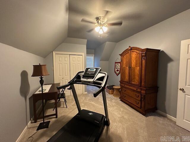 exercise area with lofted ceiling, a ceiling fan, baseboards, and light carpet