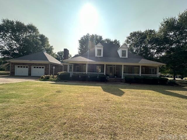 view of front of house with a garage, a front lawn, and covered porch